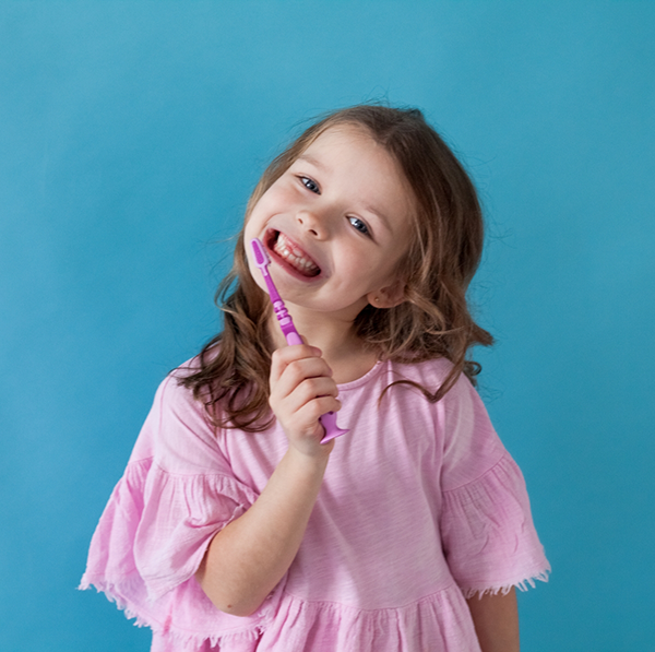 Little girl in pink shirt holding toothbrush