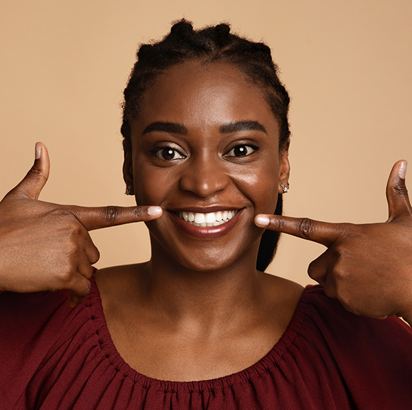 Woman in red shirt pointing to her smile