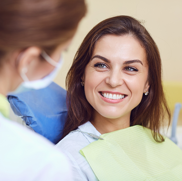 Woman in dental chair smiling at female dentist
