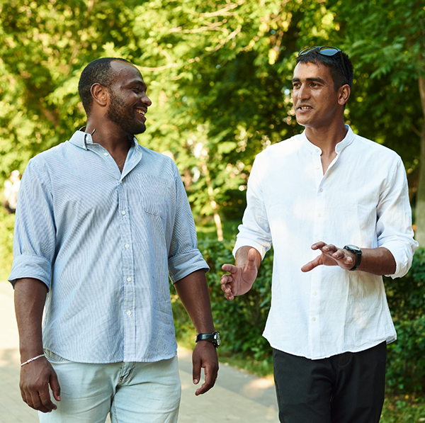 Two men taking a walk outside next to some bushes